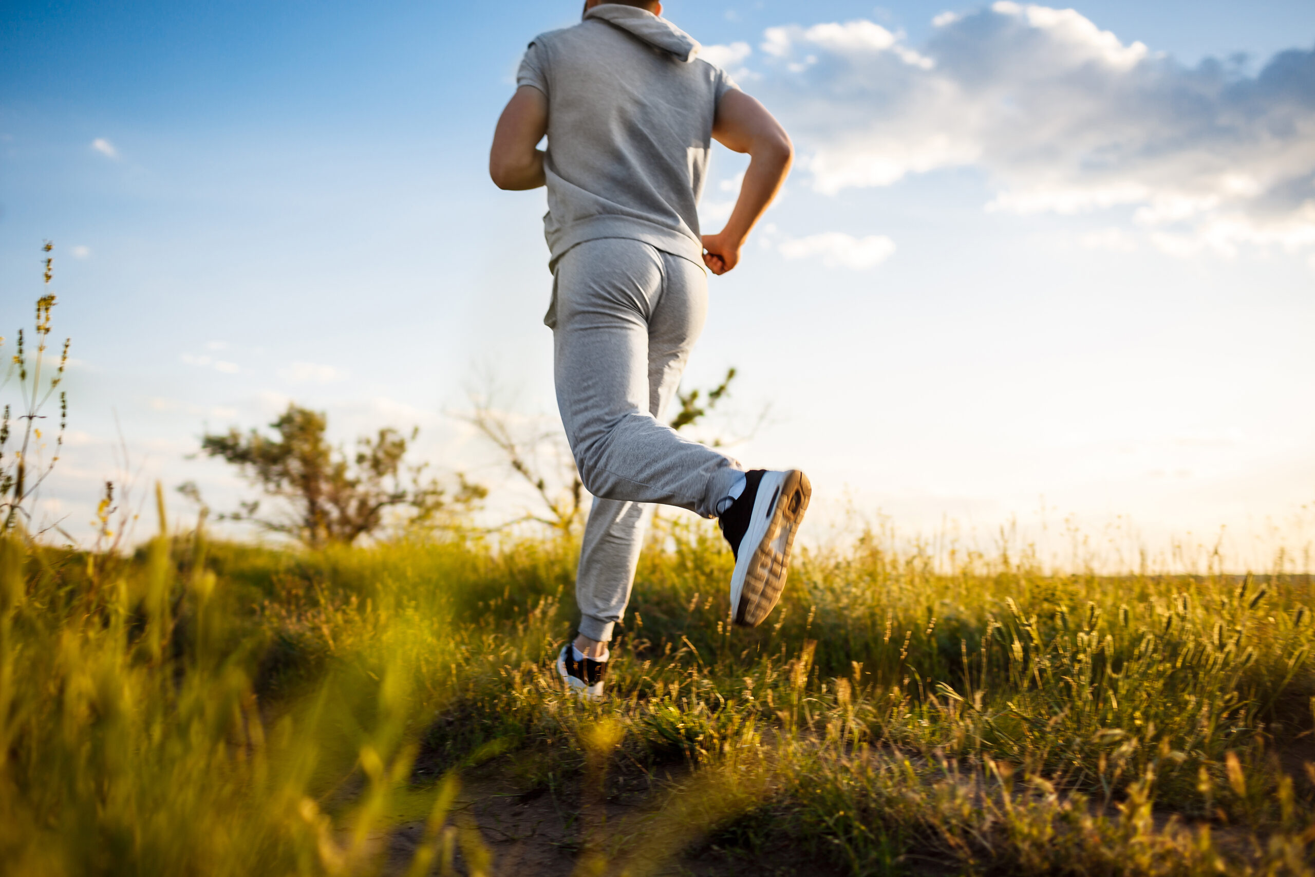 Close up of sportive man jogging in field at sunrise. Close up of sportive man jogging in field at sunrise.
