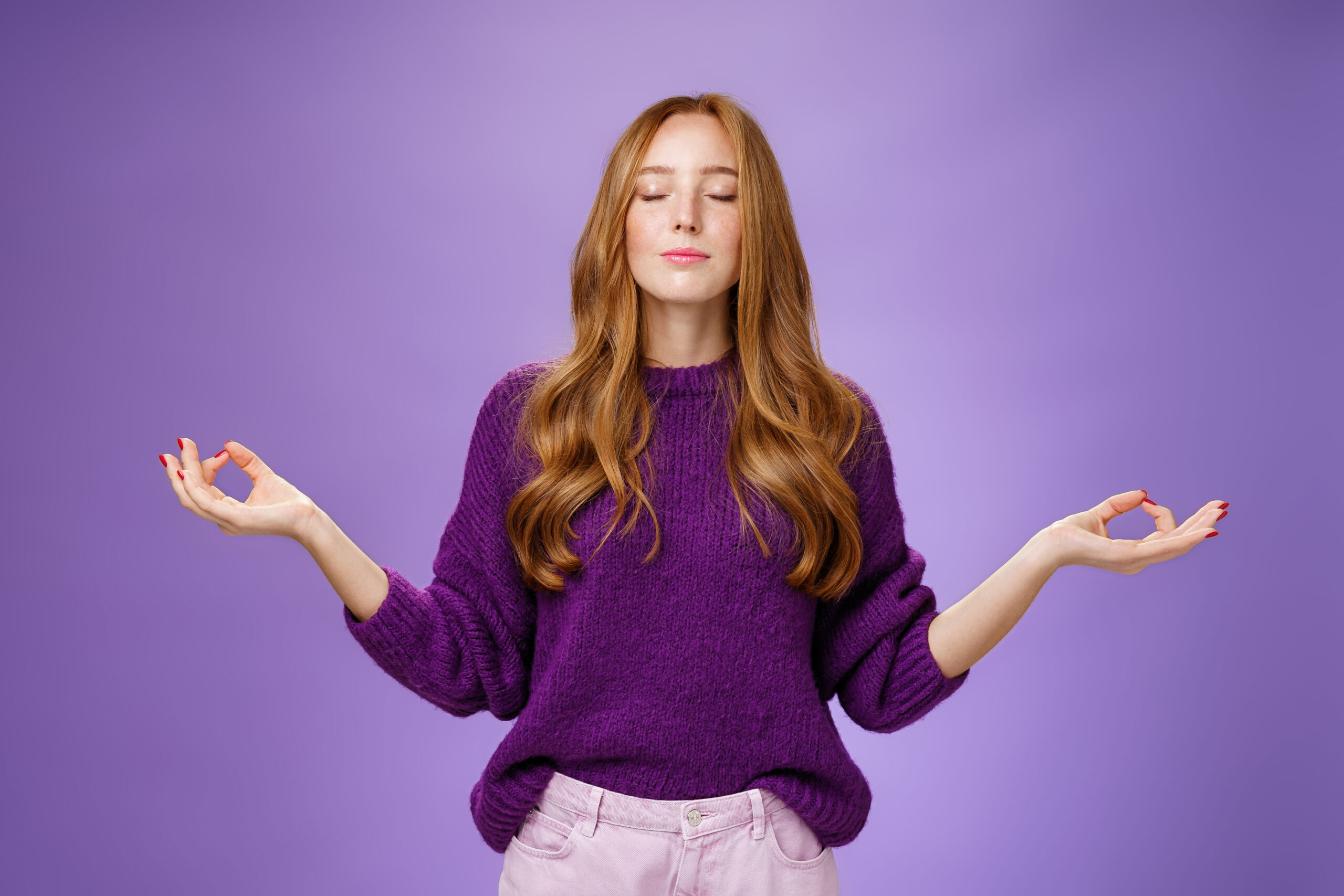 Sound mind in body. Peaceful and happy attractive female with red hair and freckles close eyes and smile from calm and relieved feelings as meditating in lotus pose with mudra gesture, doing yoga Sound mind in body. Peaceful and happy attractive female with red hair and freckles close eyes and smile from calm and relieved feelings as meditating in lotus pose with mudra gesture, doing yoga