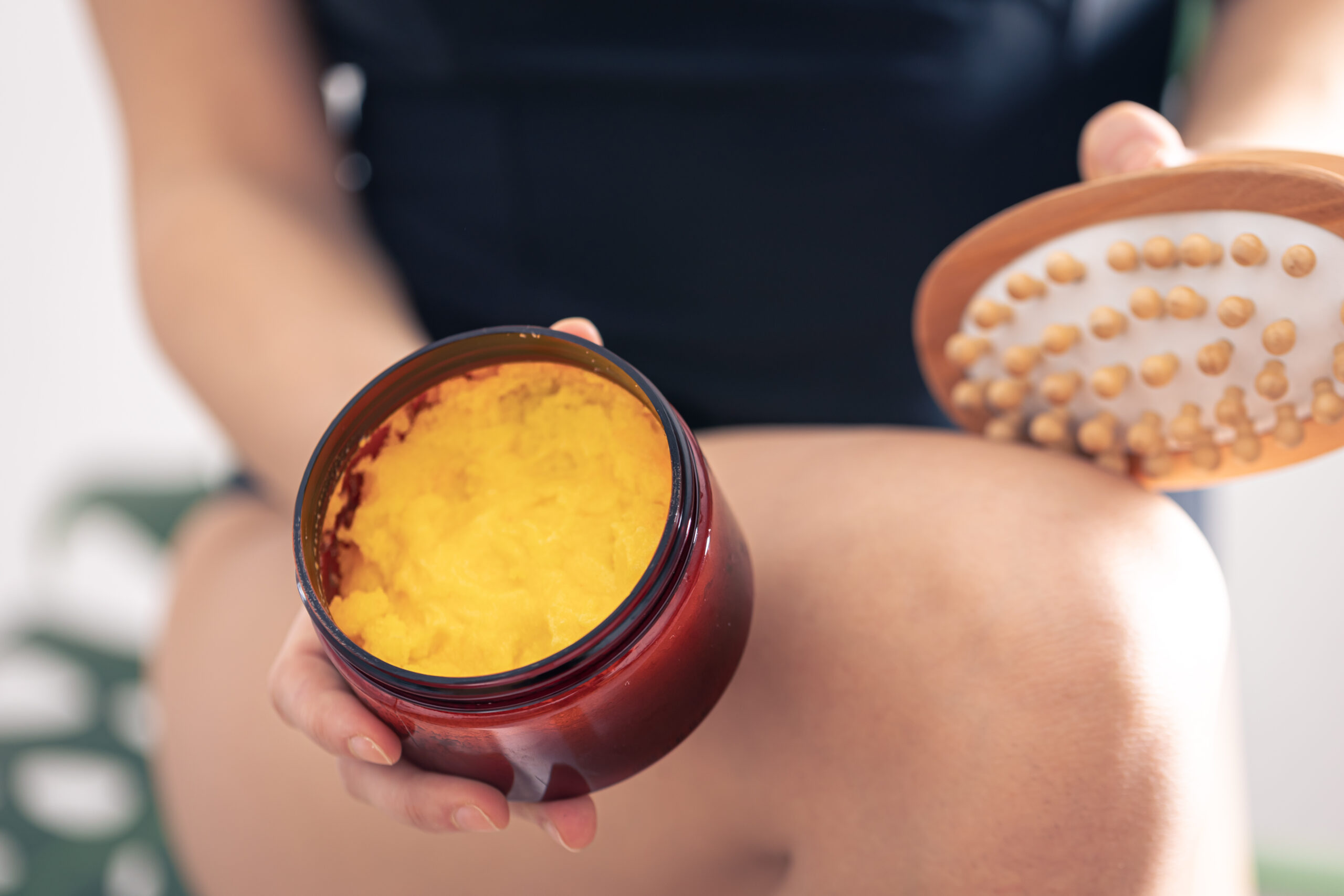 Close-up of anti-cellulite massage brush and body scrub in female hands. Close-up of anti-cellulite massage brush and body scrub in female hands.