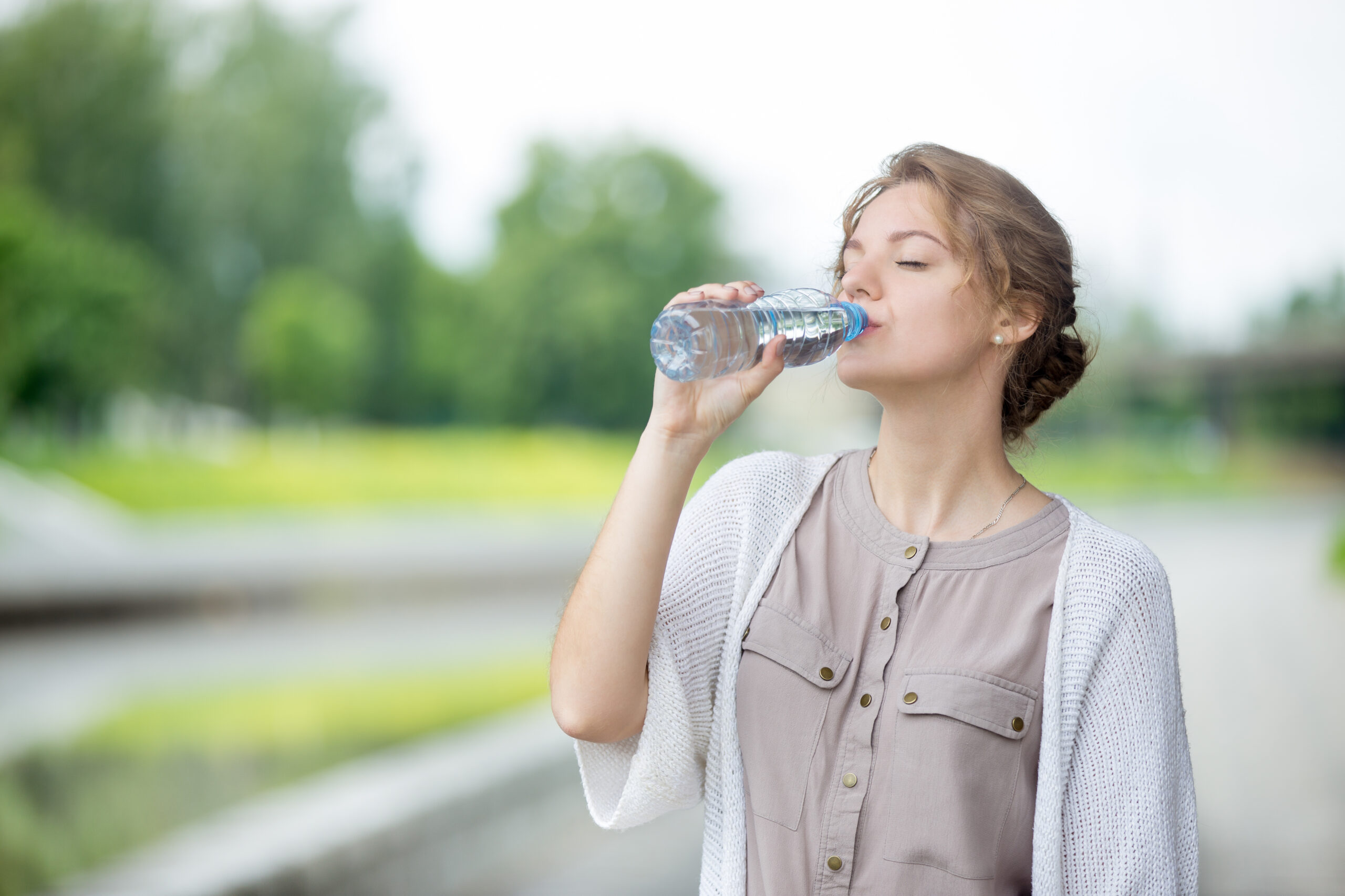 Young woman drinking water from bottle on the city street Young woman drinking water from bottle on the city street