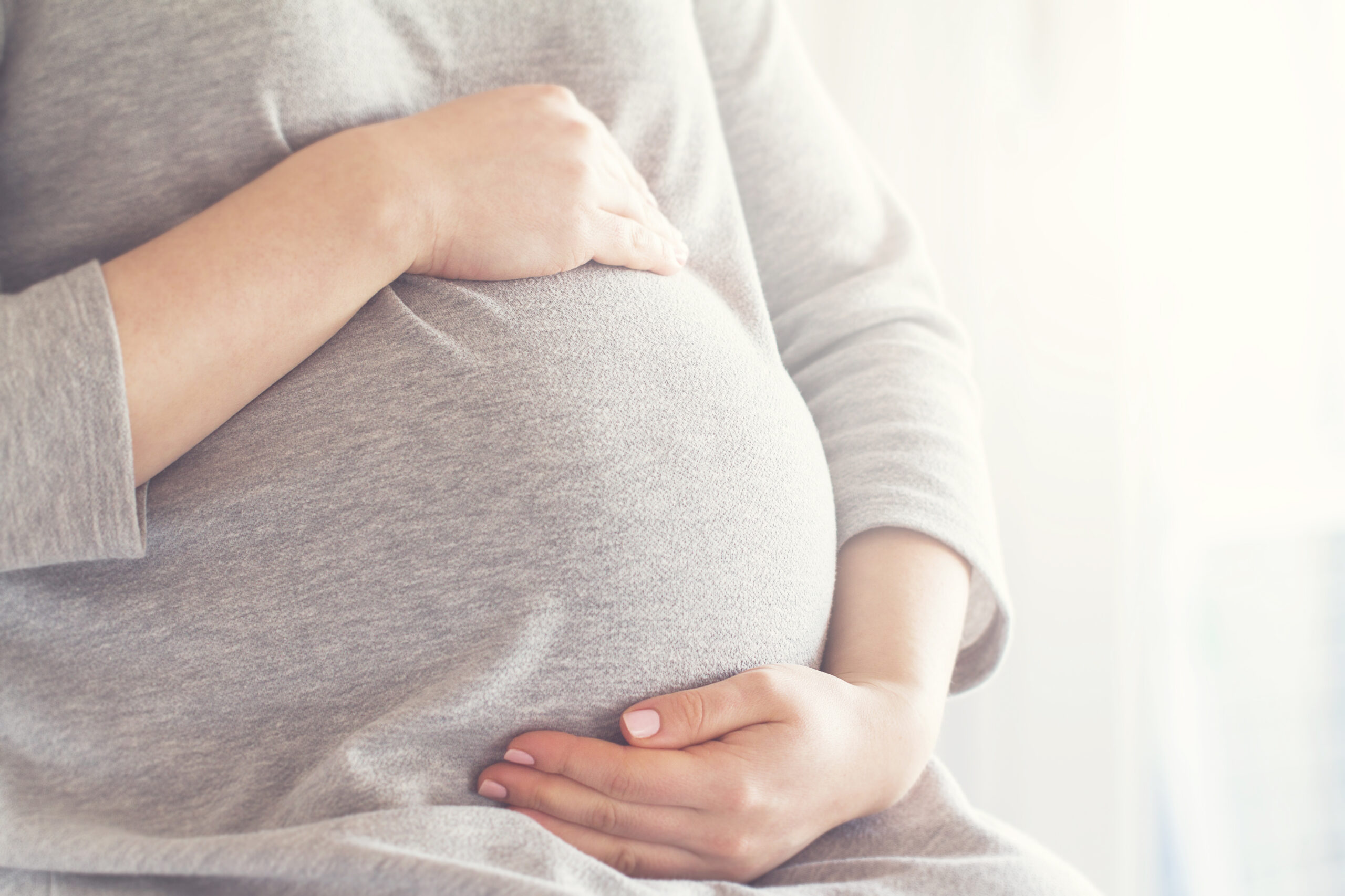 Young pregnant woman holds her hands on her swollen belly. Love Young pregnant woman holds her hands on her swollen belly. Love
