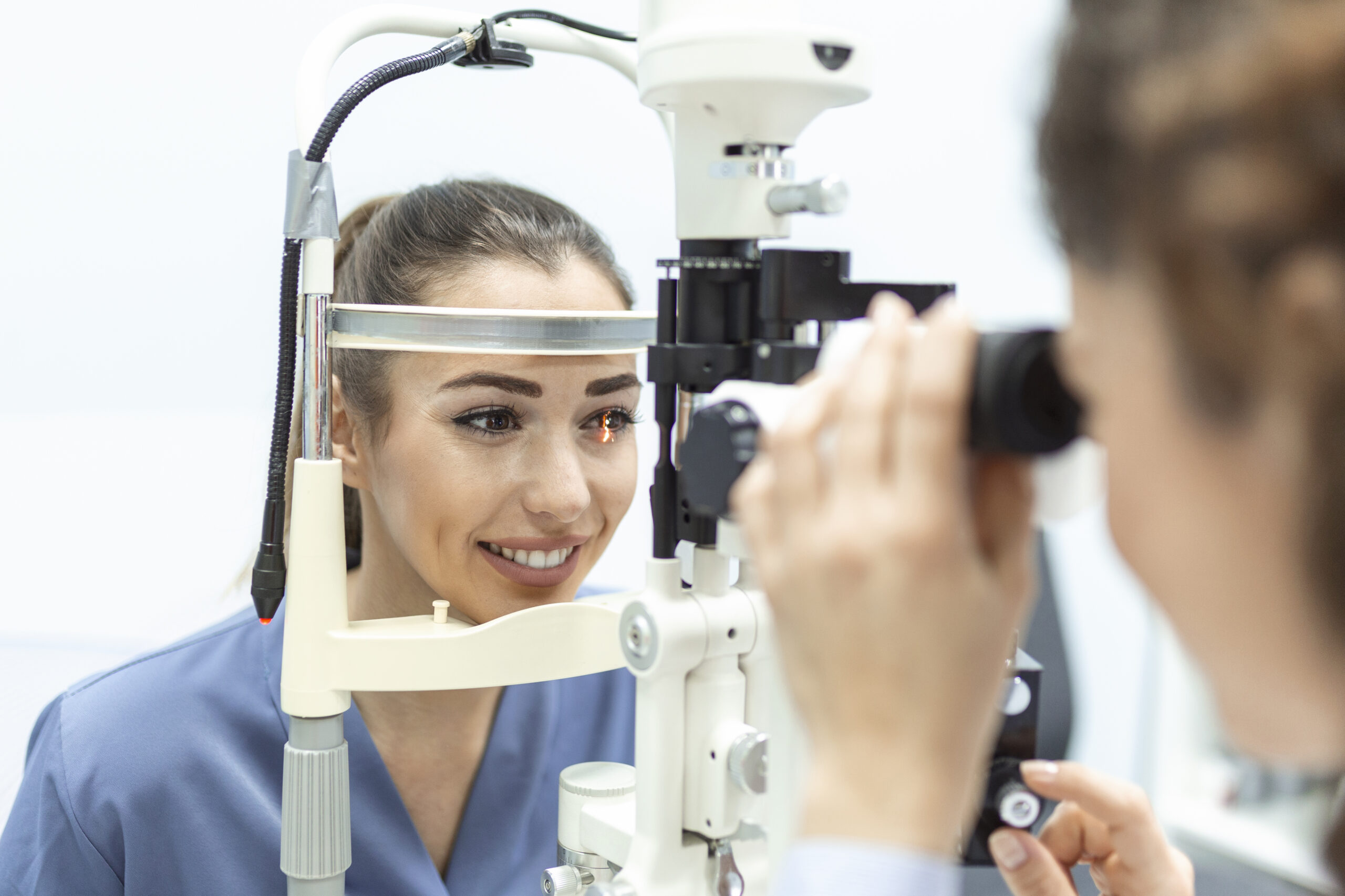 Eye doctor with female patient during an examination in modern clinic. Ophthalmologist is using special medical equipment for eye health Eye doctor with female patient during an examination in modern clinic. Ophthalmologist is using special medical equipment for eye health