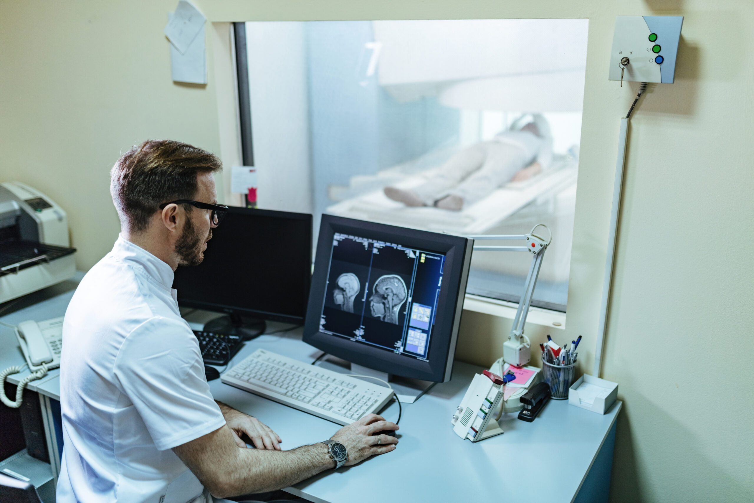 Male radiologist analyzing MRI scan results of a patient on comp Male radiologist analyzing MRI scan results of a patient on comp