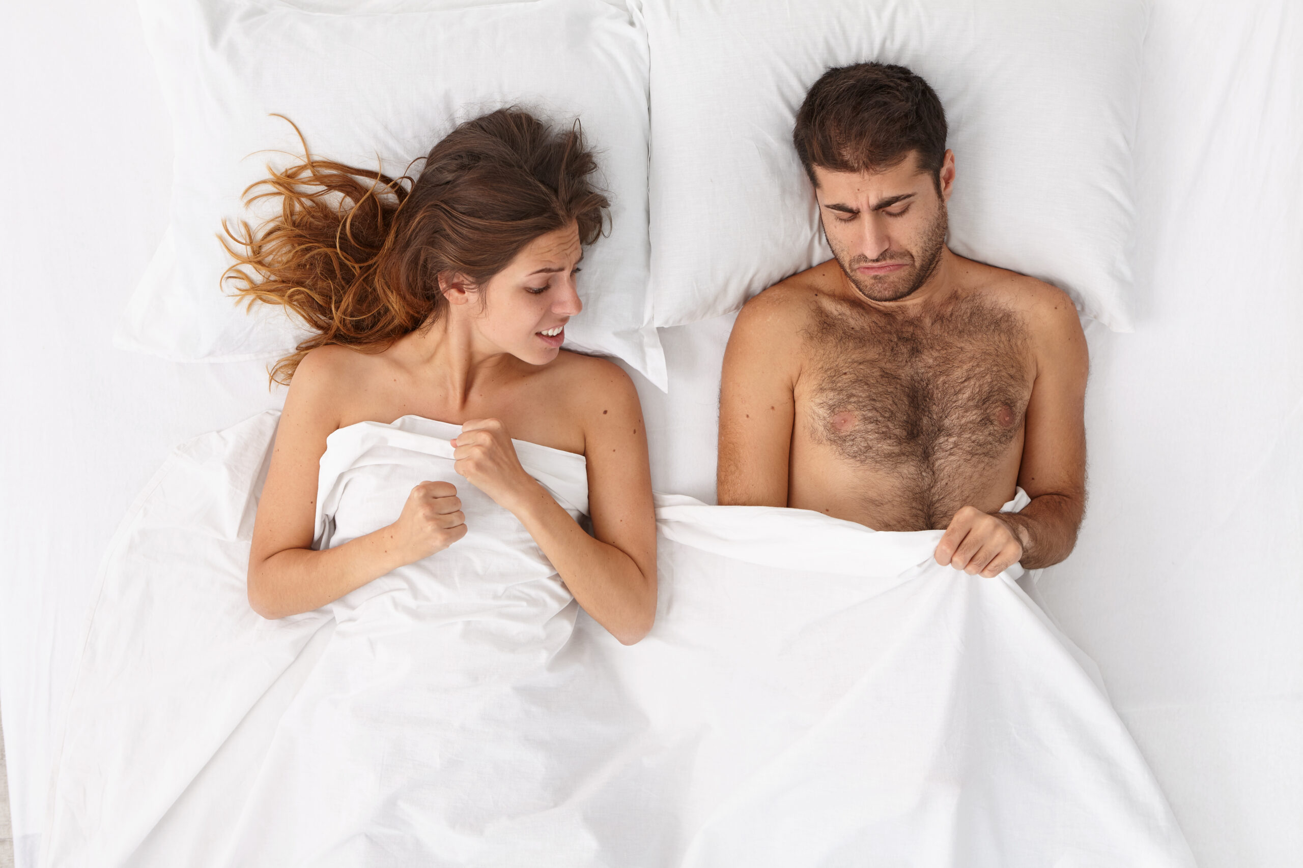 Overhead shot of displeased man has problems with reproductive system, erectile failure, suffers from impotency, hopeful woman supports him, disappointed with tiny man size. Sexual life disorder Overhead shot of displeased man has problems with reproductive system, erectile failure, suffers from impotency, hopeful woman supports him, disappointed with tiny man size. Sexual life disorder