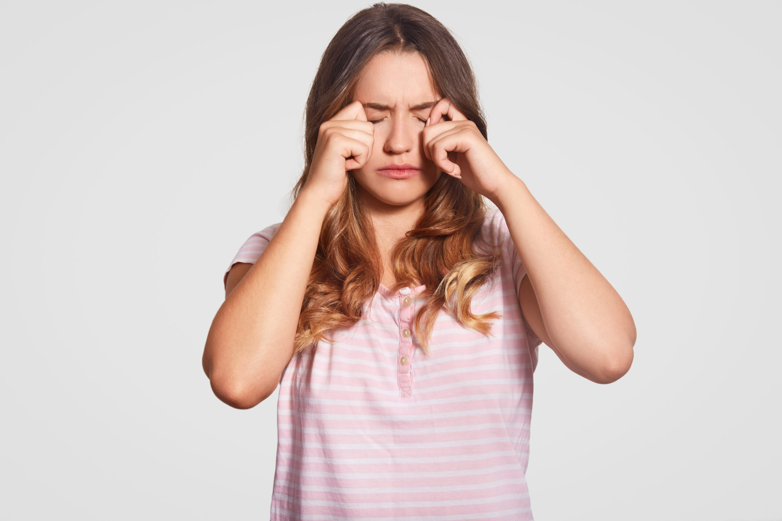 Photo of displeased young girl rubs eyes, being in low spirit, wears casual domestic clothes, poses against white background. Woman had bad sleep at night. Bedding concept. People and tiredness Photo of displeased young girl rubs eyes, being in low spirit, wears casual domestic clothes, poses against white background. Woman had bad sleep at night. Bedding concept. People and tiredness