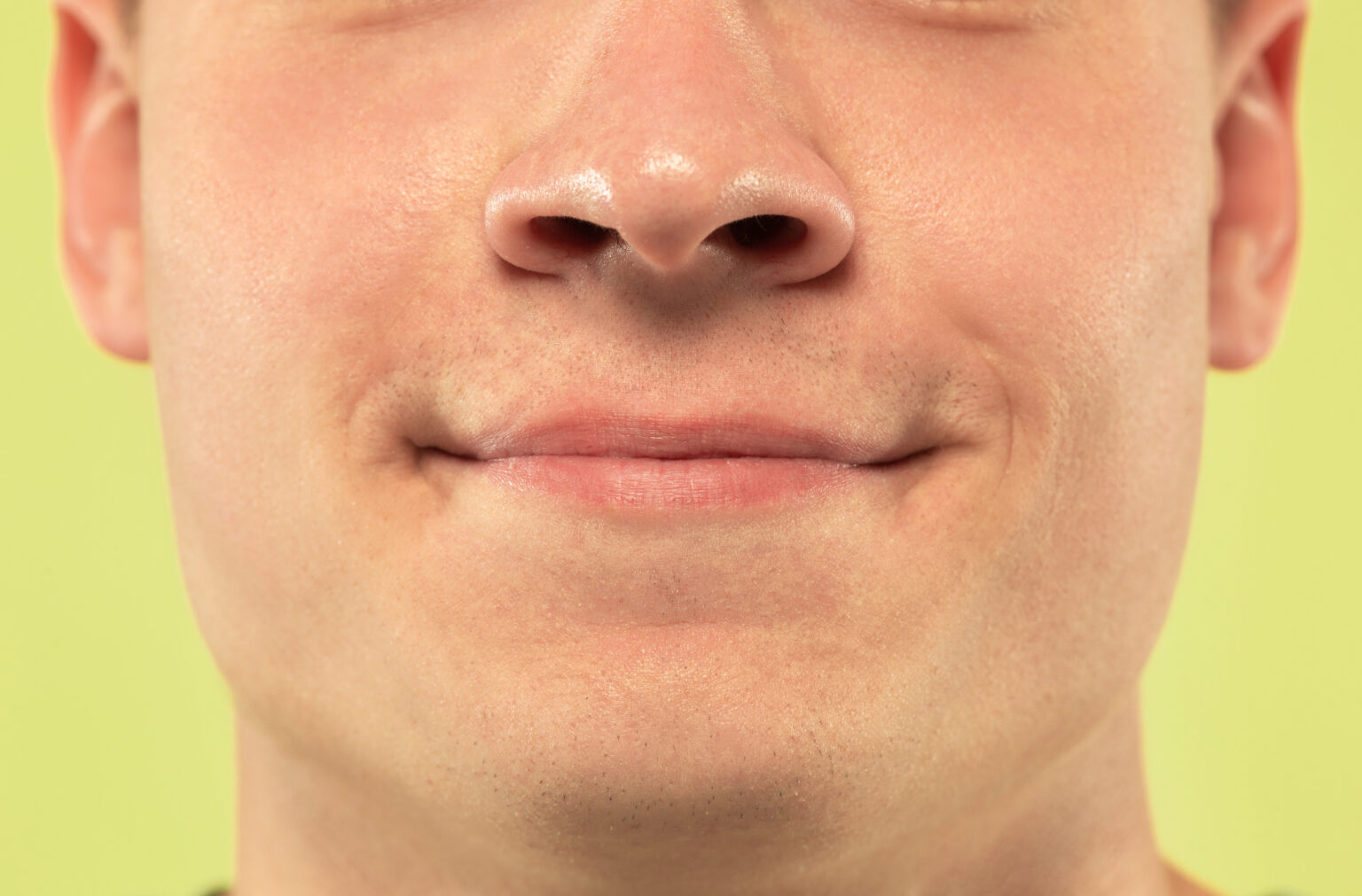 Caucasian young man’s close up shot on green background Caucasian young man’s close up shot on green background