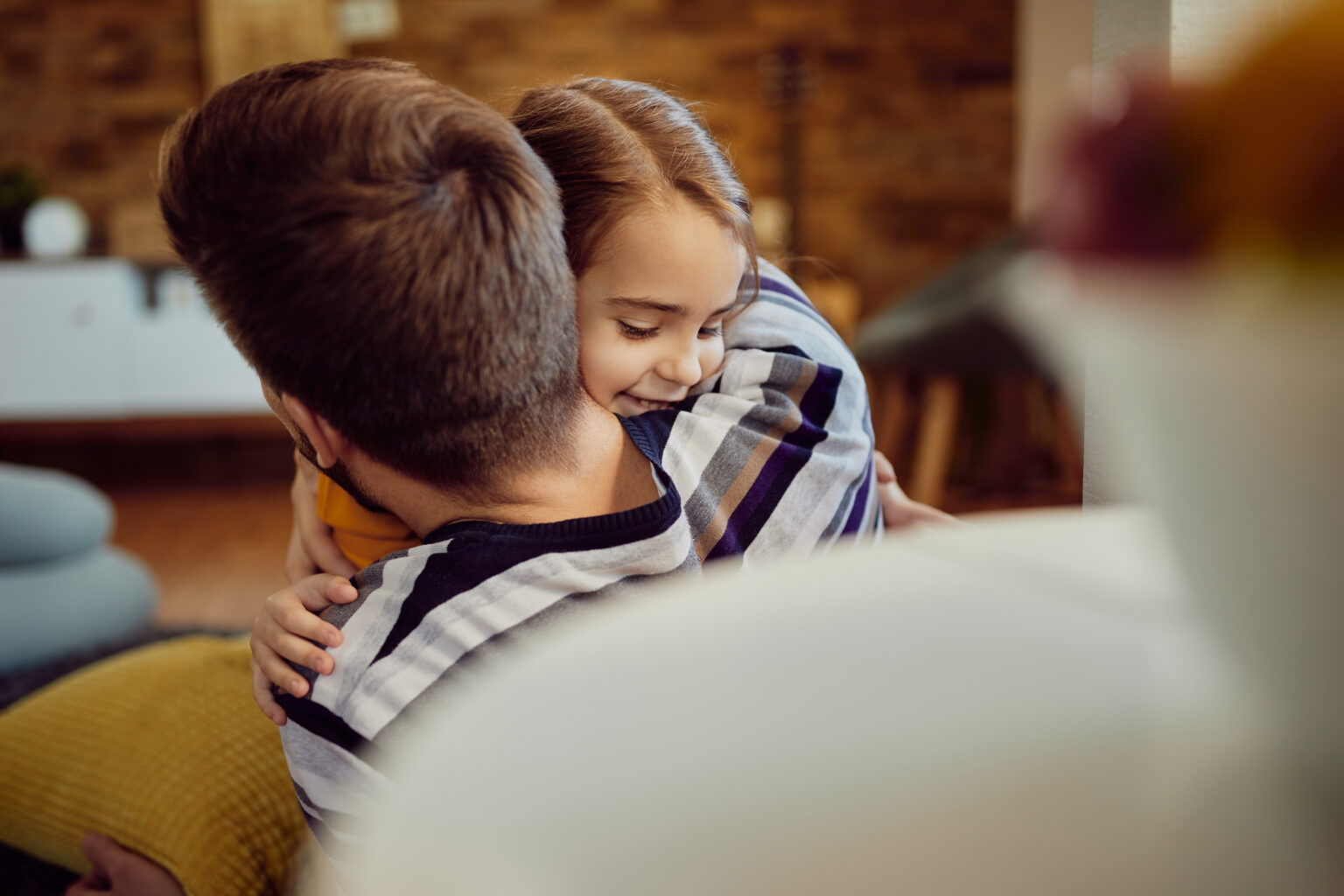Happy daughter embracing her father at home.
