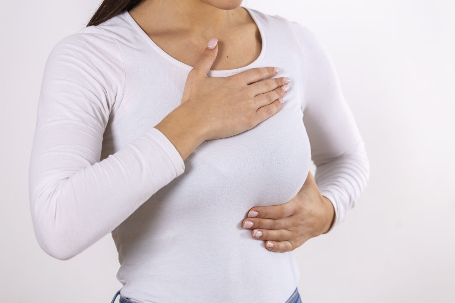 Woman hand checking lumps on her breast for signs of breast cancer on gray background. Healthcare concept. Close-up Of A Woman’s Hand On Breast Showing Cancer Symptom Woman hand checking lumps on her breast for signs of breast cancer on gray background. Healthcare concept. Close-up Of A Woman’s Hand On Breast Showing Cancer Symptom