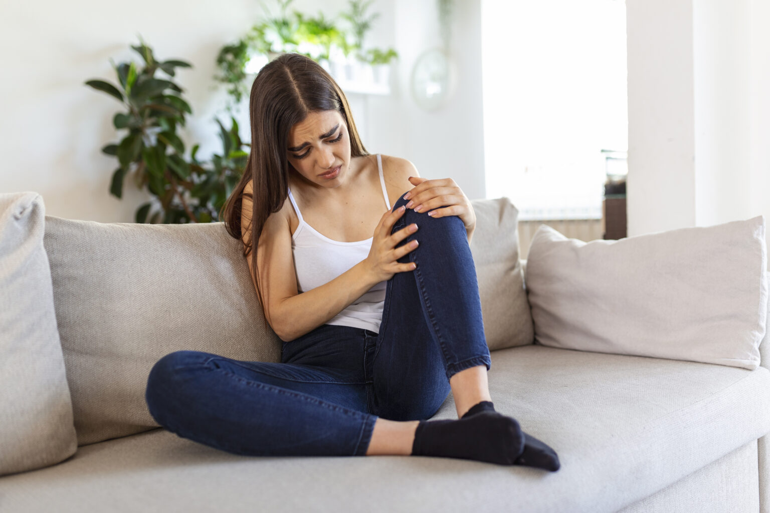 woman holding the knee with pain on sofa,health care and medical concept. woman holding the knee with pain on sofa,health care and medical concept.