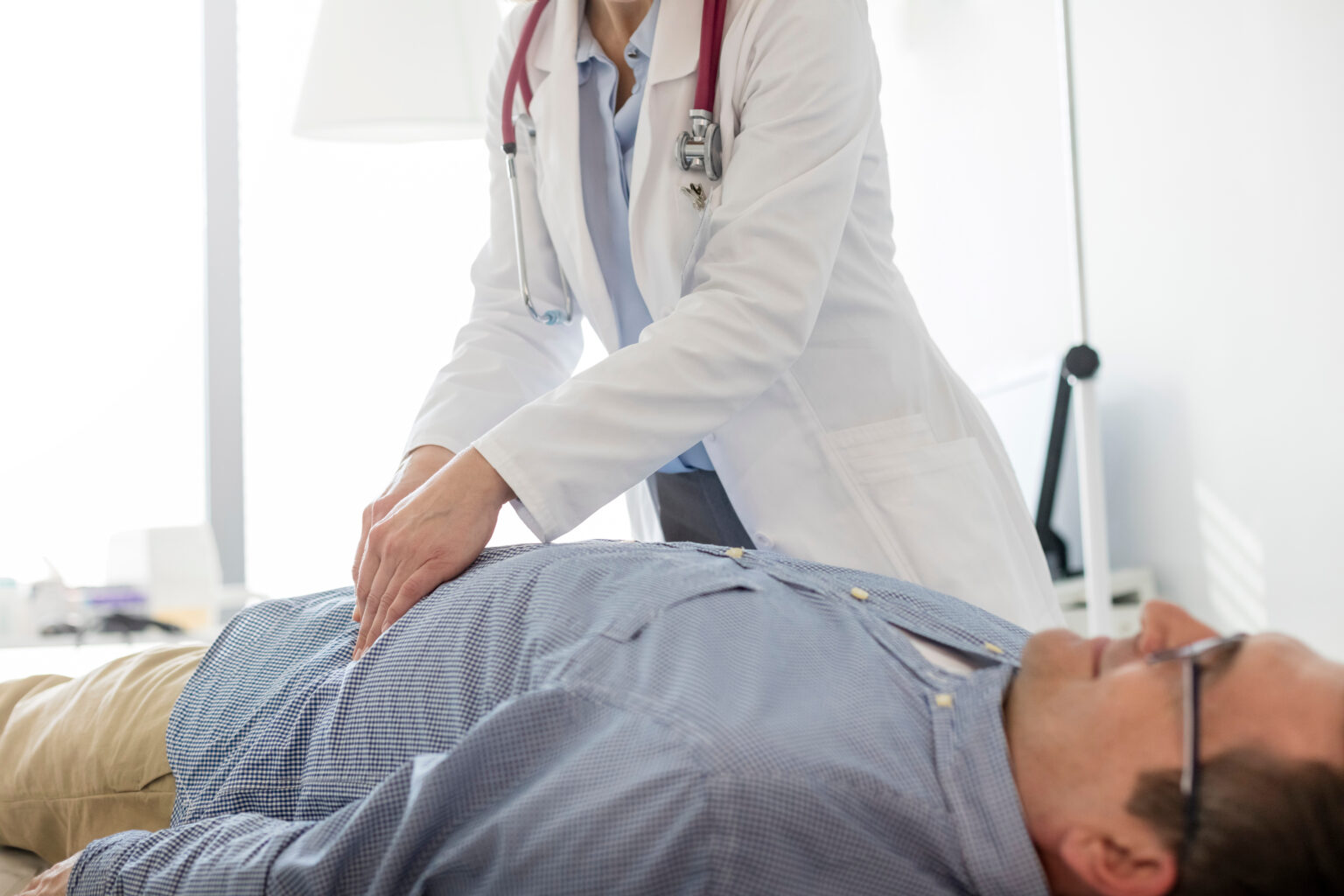 Doctor,Analyzing,Abdomen,Of,Patient,In,Examination,Room,At,Hospital Doctor,Analyzing,Abdomen,Of,Patient,In,Examination,Room,At,Hospital