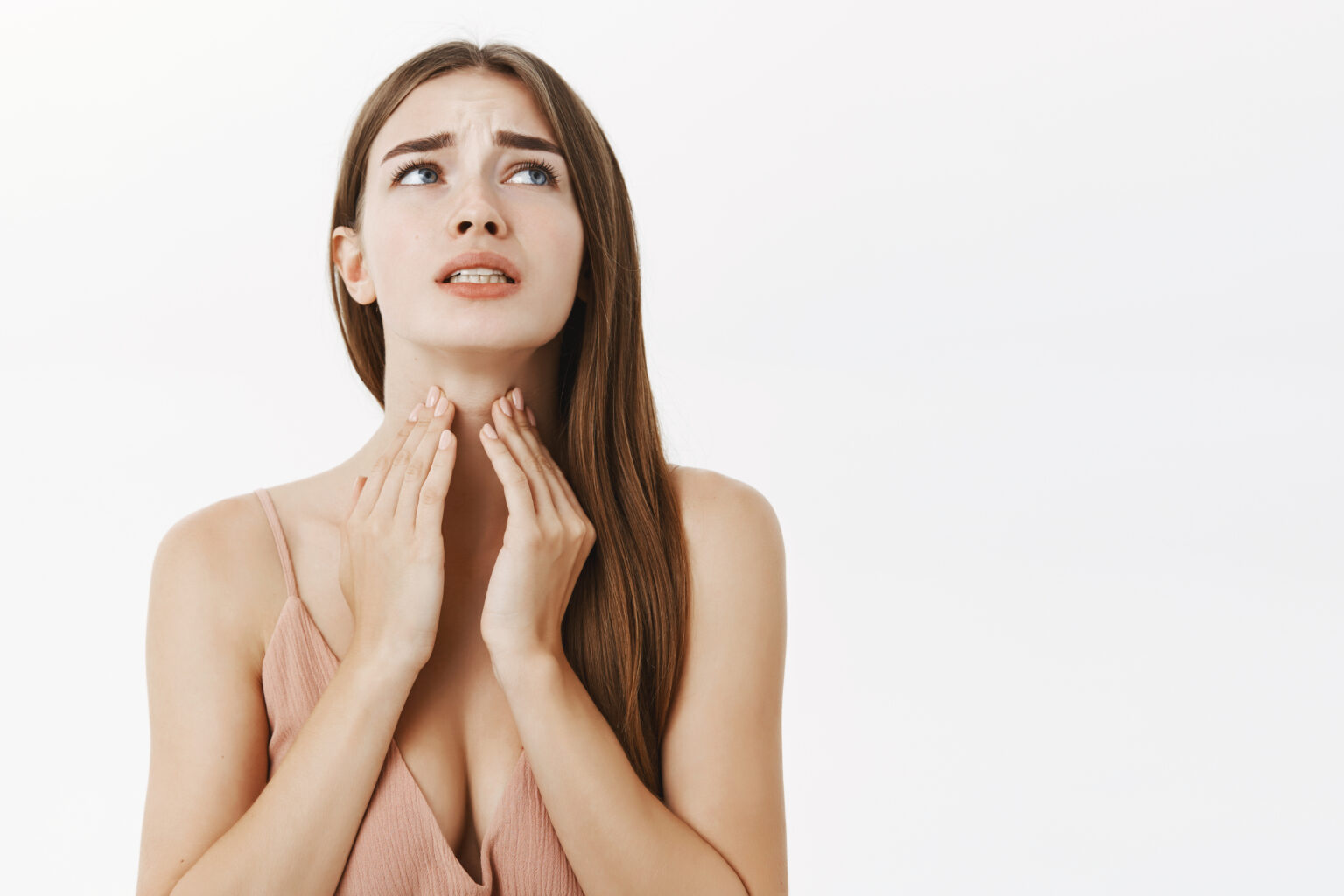 Woman getting ill before important meeting feeling discomfort and suffering from pain in throat touching neck frowning an clenching teeth from terrible feeling posing over gray background Woman getting ill before important meeting feeling discomfort and suffering from pain in throat touching neck frowning an clenching teeth from terrible feeling posing over gray background