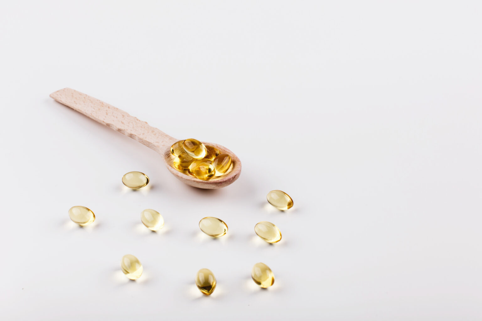 Oil capsule for hair with vitamin E lie on wooden spoon Oil capsule for hair with vitamin E lie on wooden spoon