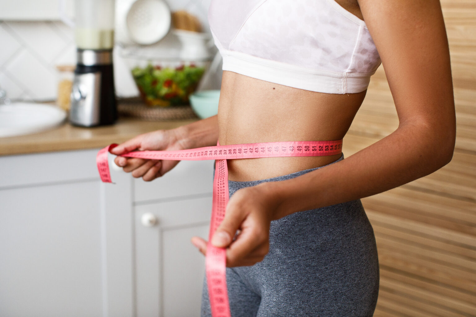 African woman is measuring her waist with a centimeter African woman is measuring her waist with a centimeter