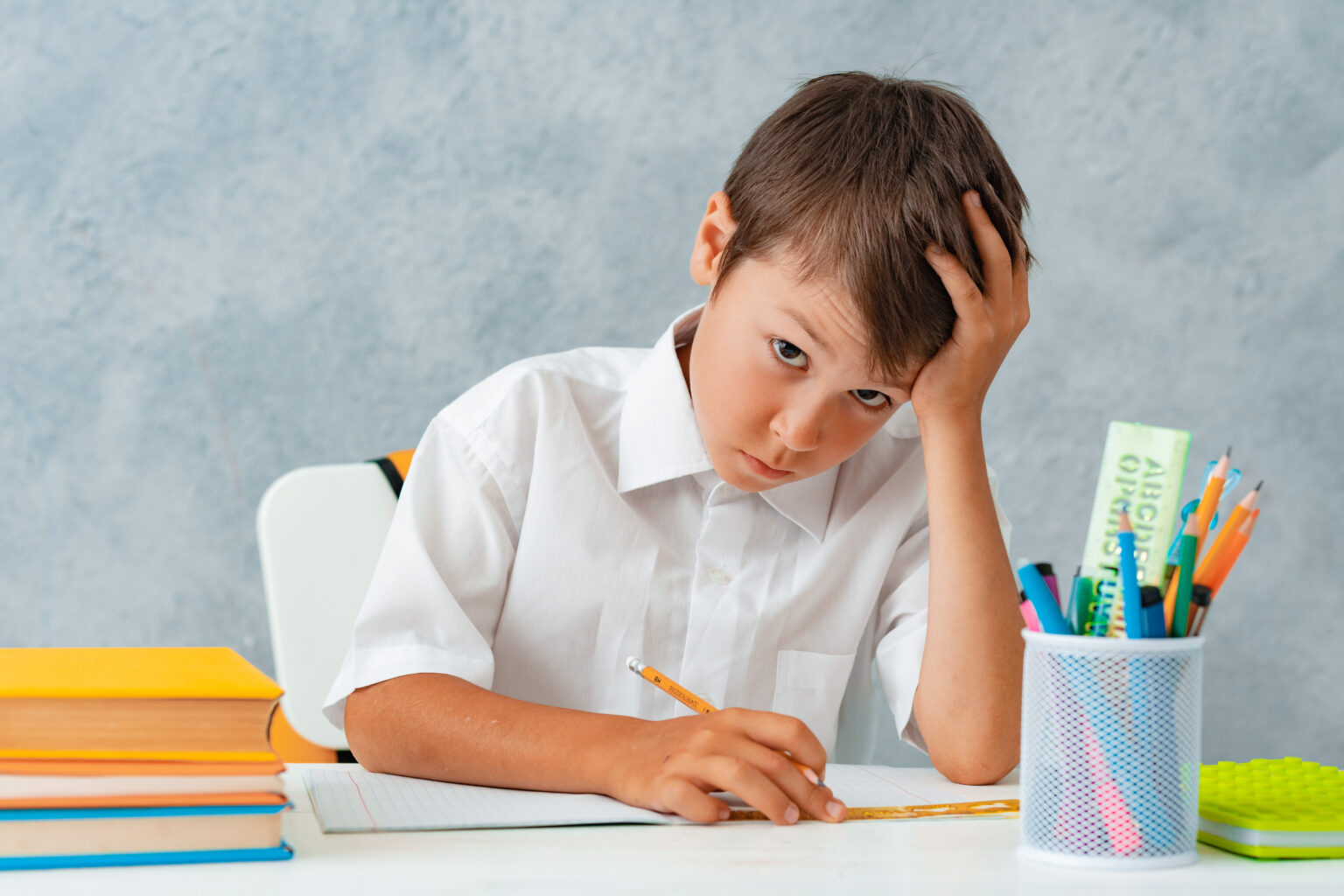 Back to school. Happy smiling student draws at the Desk. A schoolboy solves his homework. A boy from elementary school Back to school. Happy smiling student draws at the Desk. A schoolboy solves his homework. A boy from elementary school