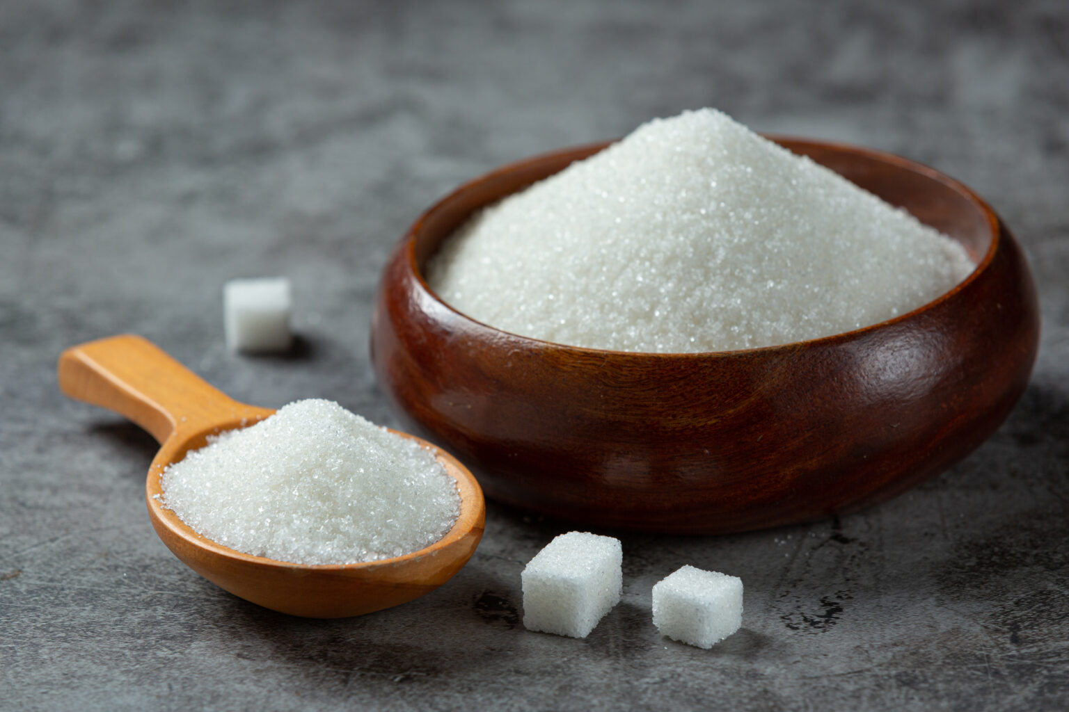 World diabetes day; sugar in wooden bowl on dark background World diabetes day; sugar in wooden bowl on dark background