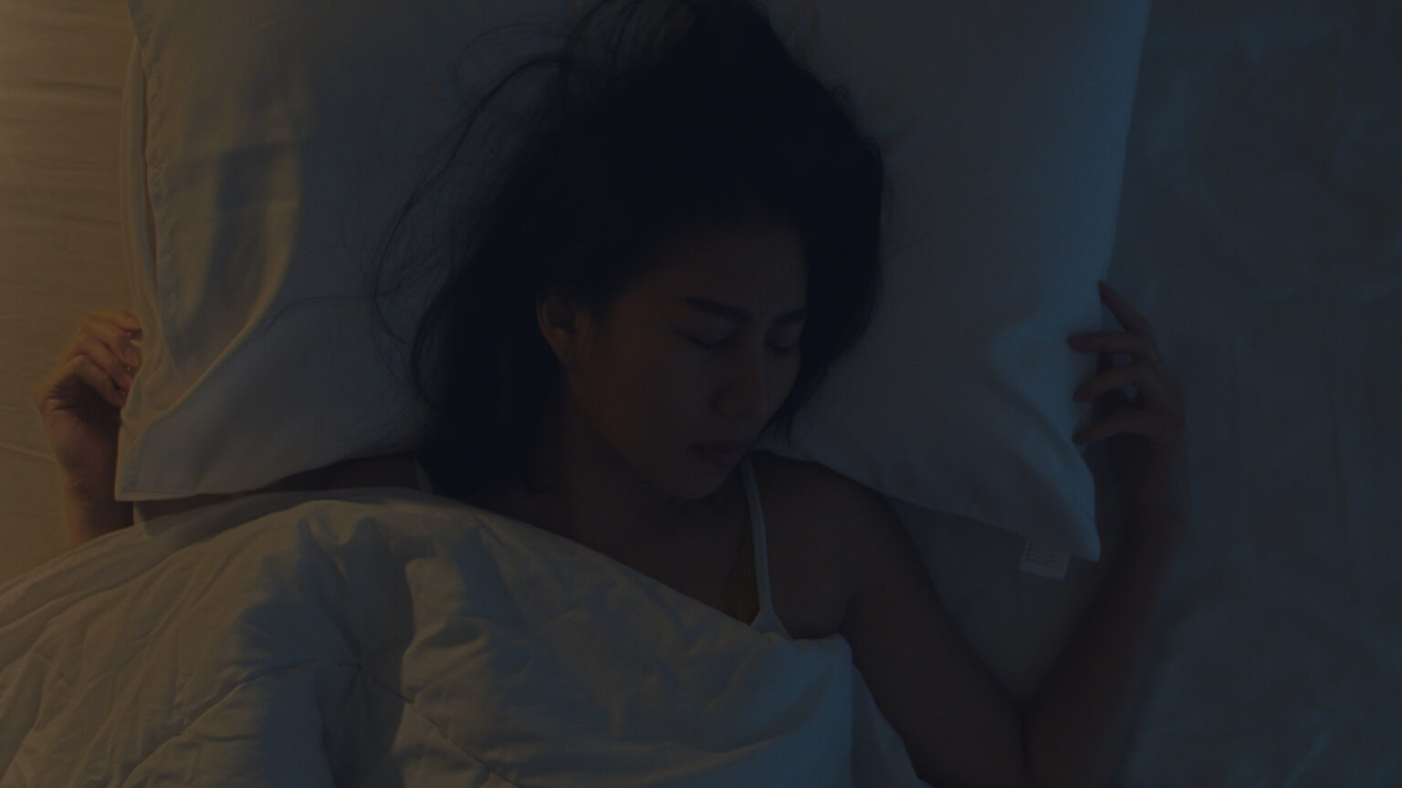Nervous young Asian woman having a nightmare lying on bed in her Nervous young Asian woman having a nightmare lying on bed in her