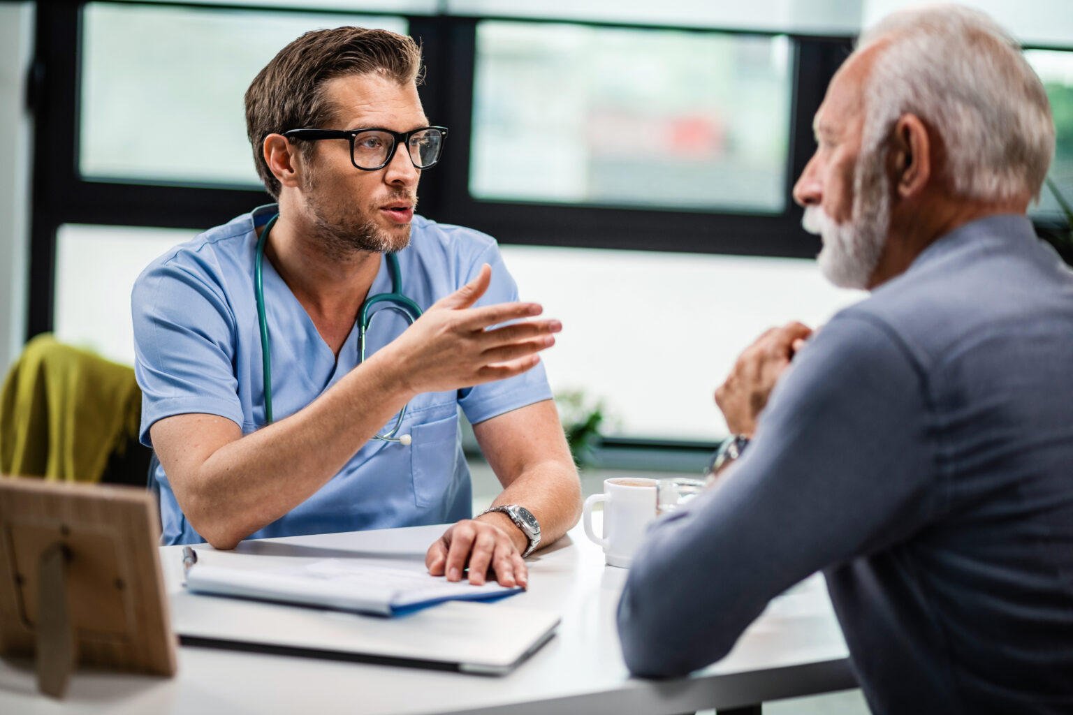 Male doctor communicating with senior patient during medical consultations at his office. Male doctor communicating with senior patient during medical consultations at his office.