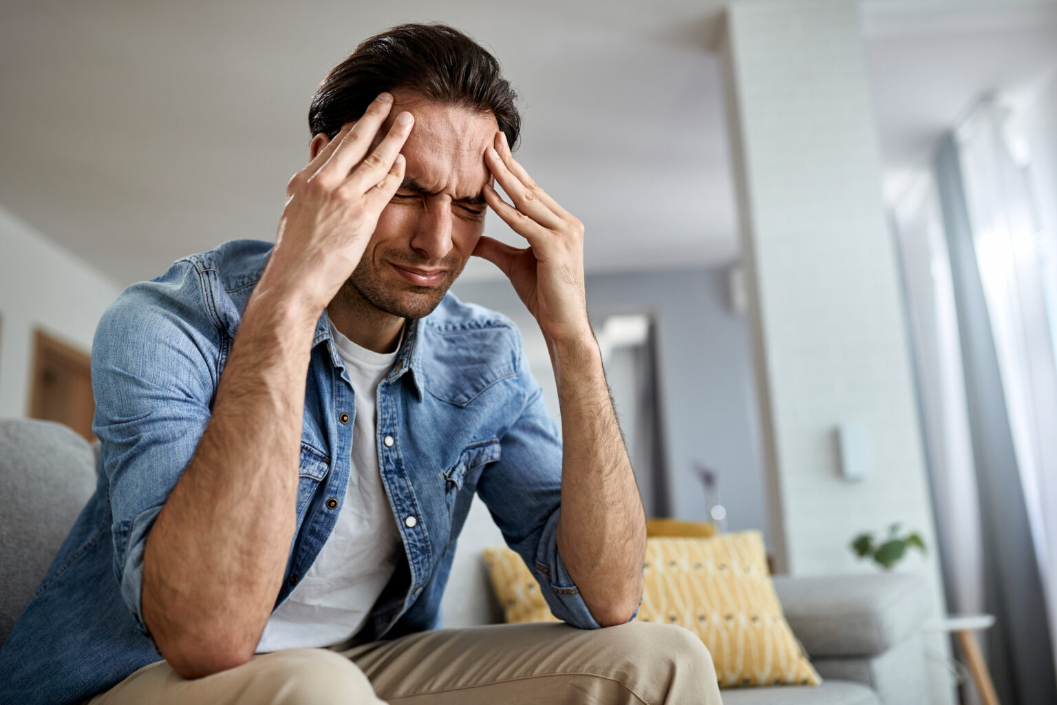 Below view of a man having a headache while being at home.