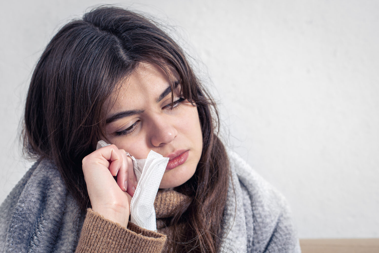 A sick young woman at home on the sofa with a cold, copy space. A sick young woman at home on the sofa with a cold, copy space.