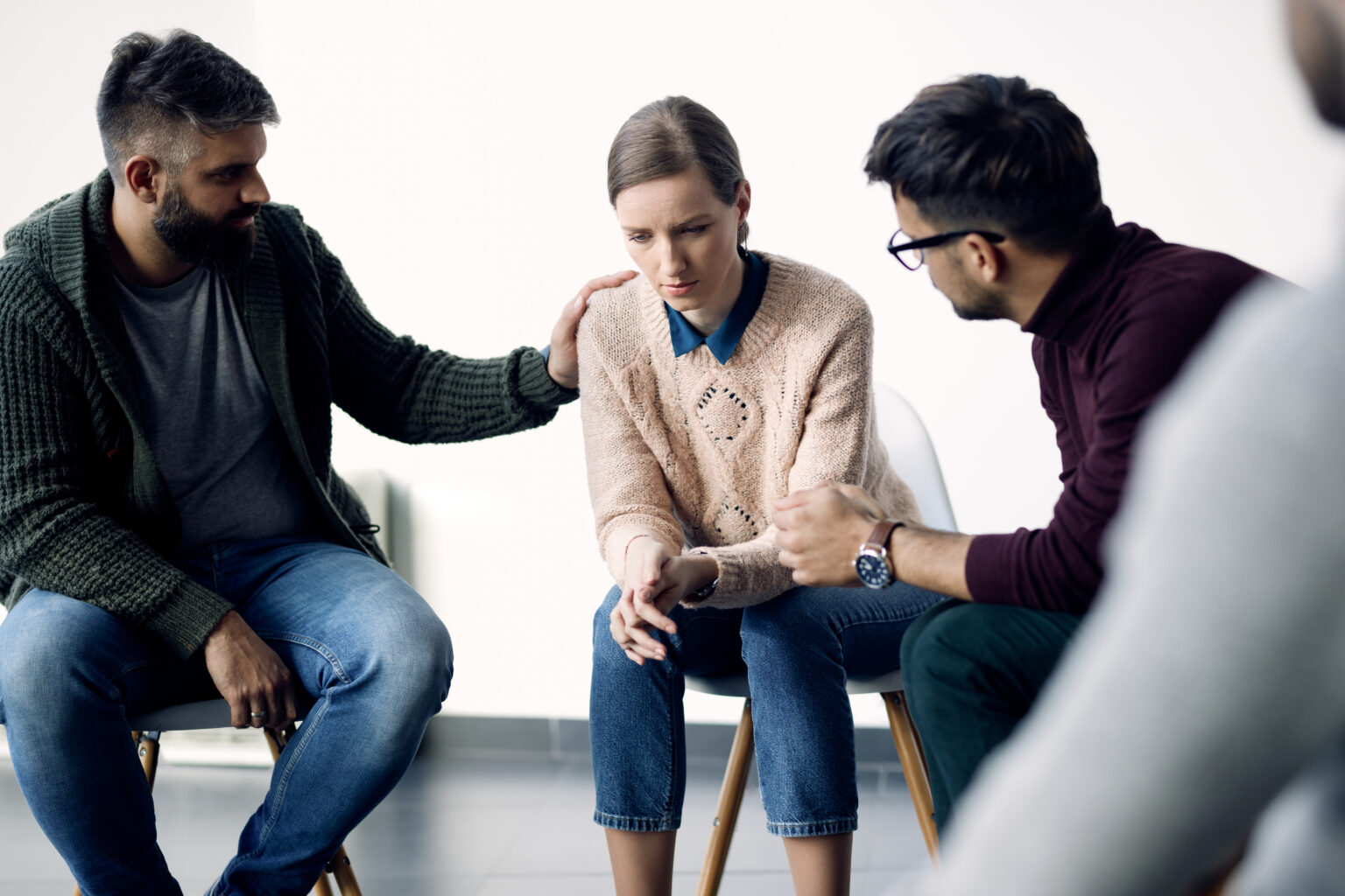Young sad woman being consoled during group therapy counselling.