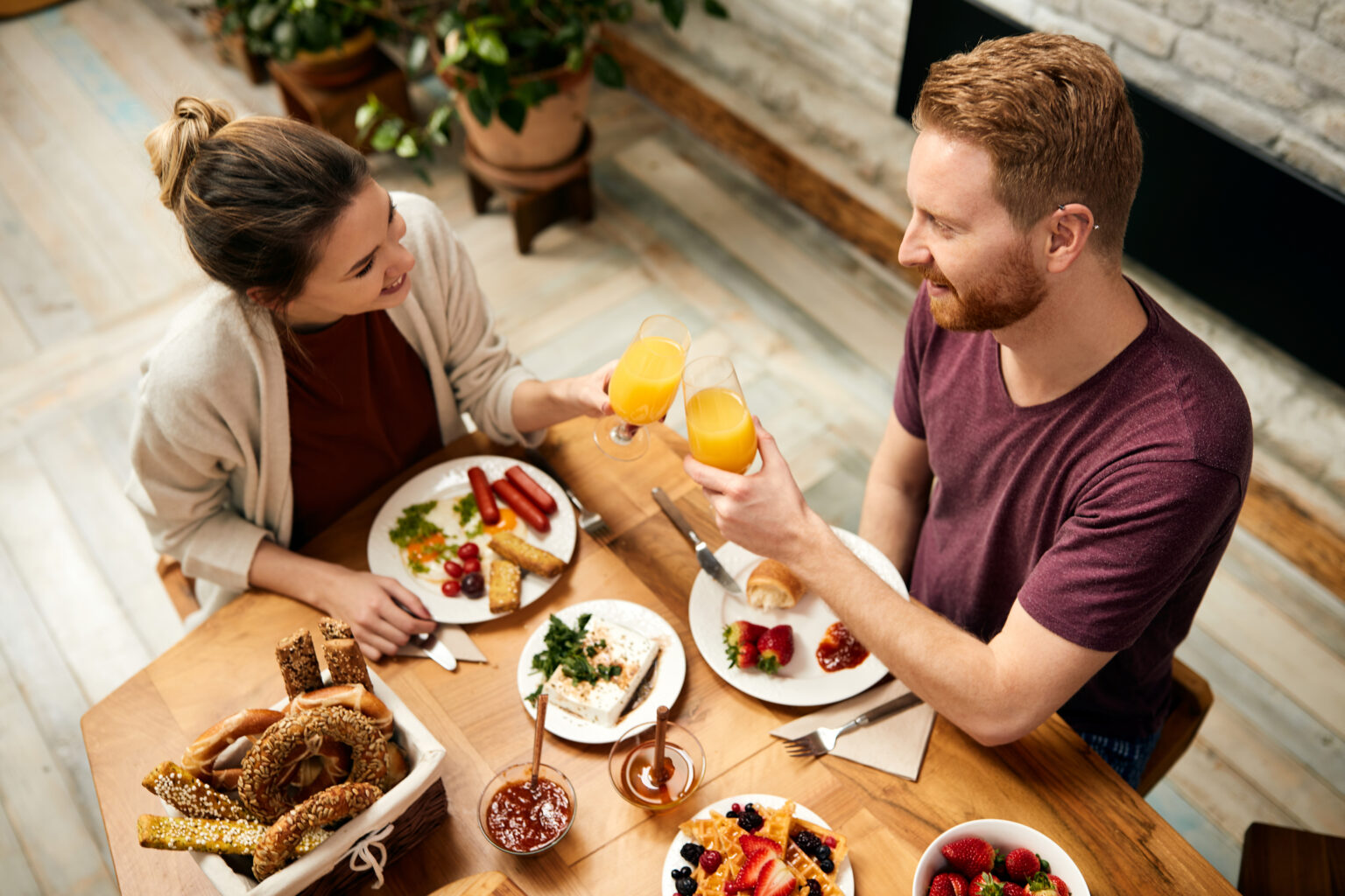 Happy couple toasting with orange juice during breakfast at home Happy couple toasting with orange juice during breakfast at home