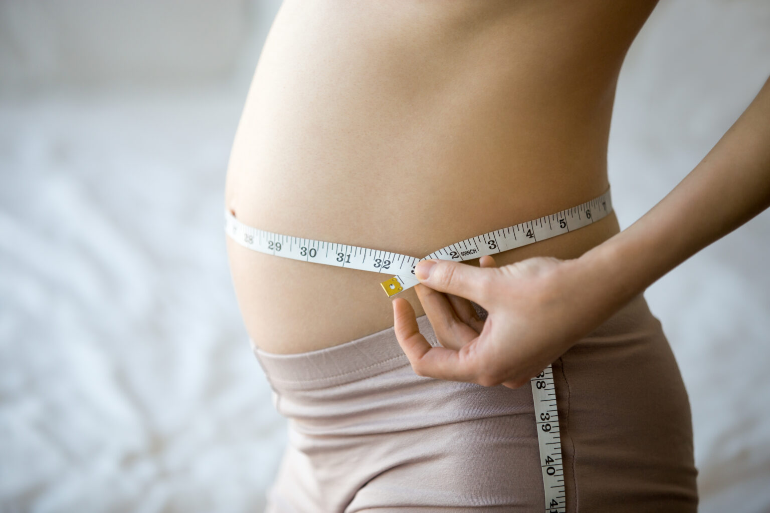 Pregnant woman measuring her waist Pregnant woman measuring her waist