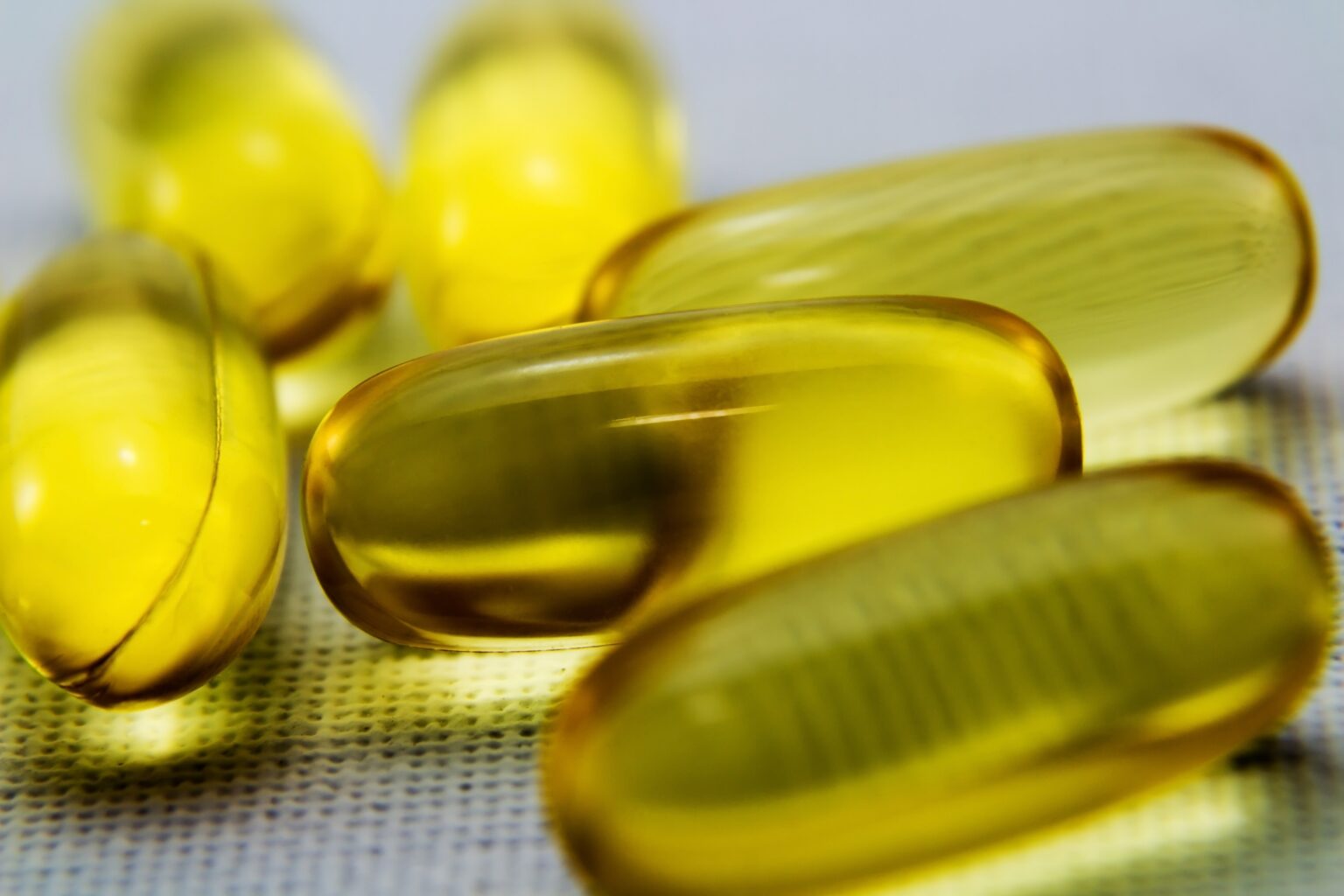 Closeup shot of some yellow transparent capsules on a white surface
